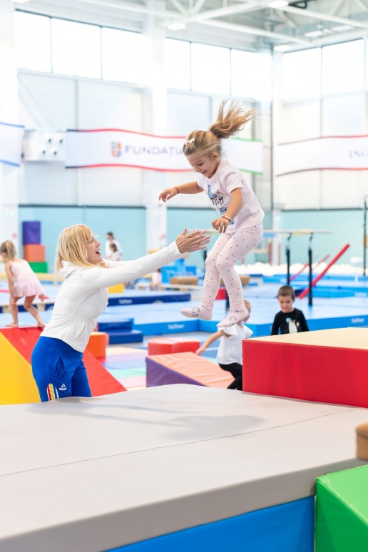 Nadia Comăneci îndrumând un copil în timpul unui exercițiu de gimnastică